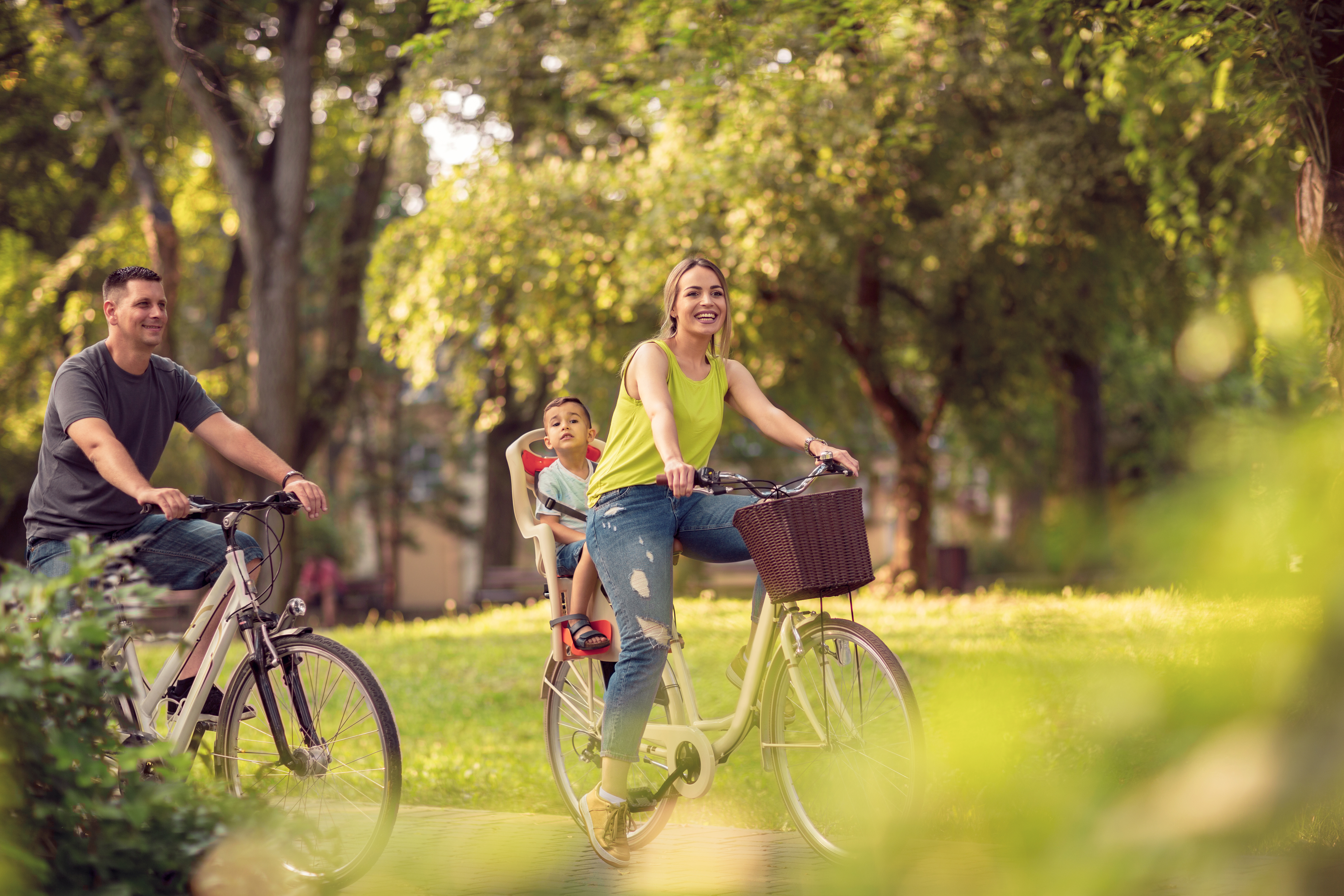 Smiling active father and mother with kid on bicycles having fun in park. Immobilier locatif à Cholet