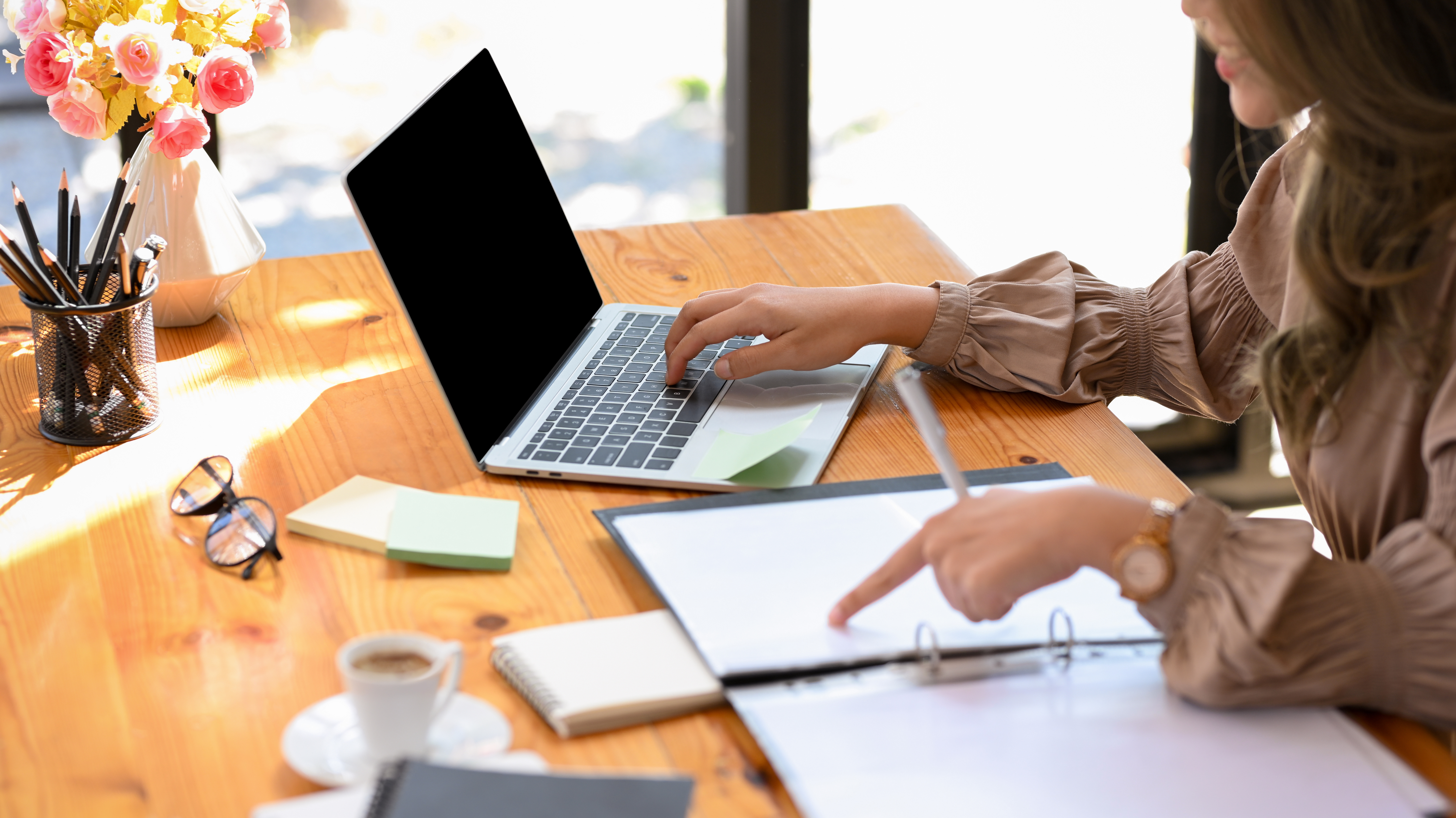Close-up image, A female employee in the management team checks and compares the details on a document paperwork between laptops.
