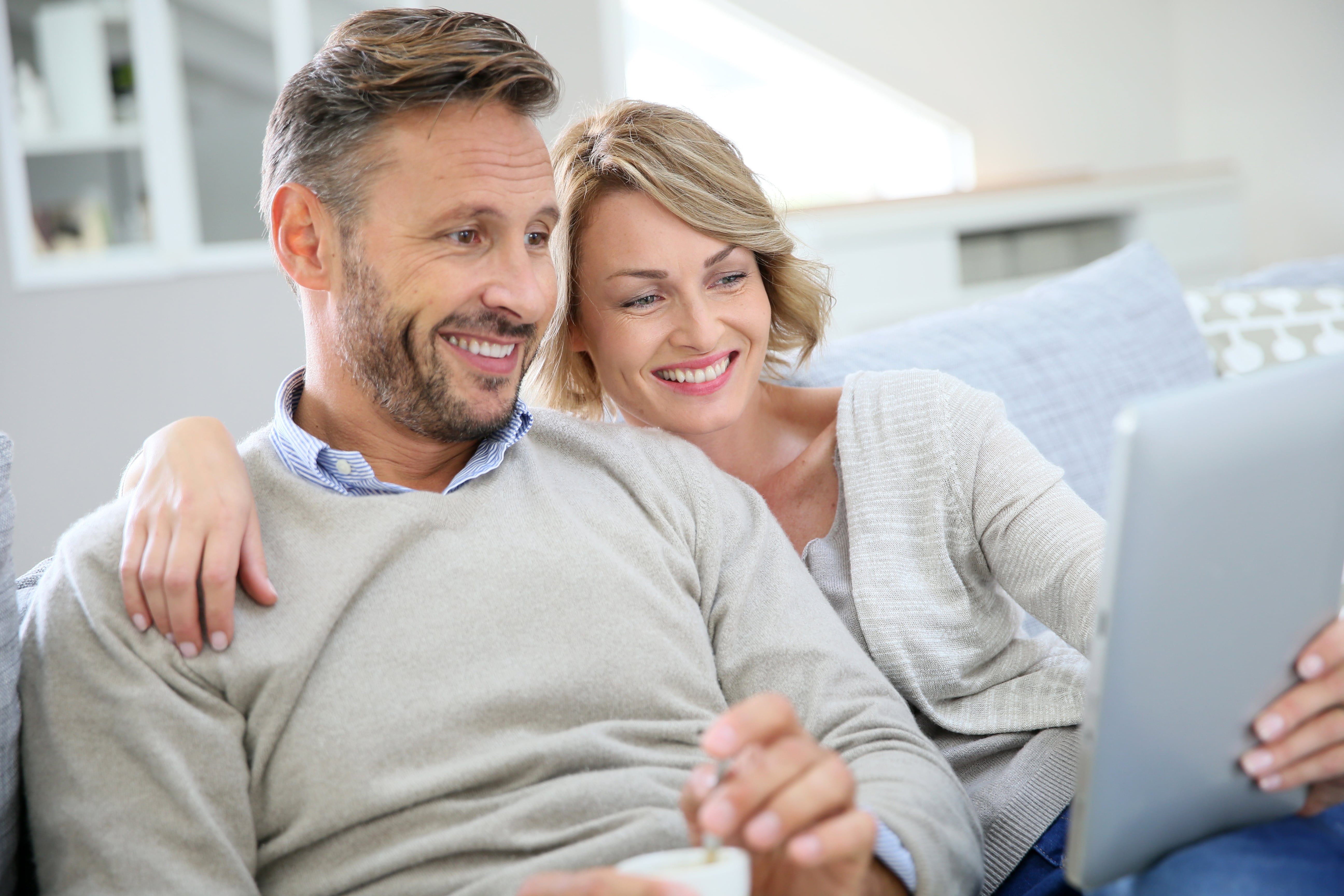 Middle-aged couple relaxing in sofa and using tablet